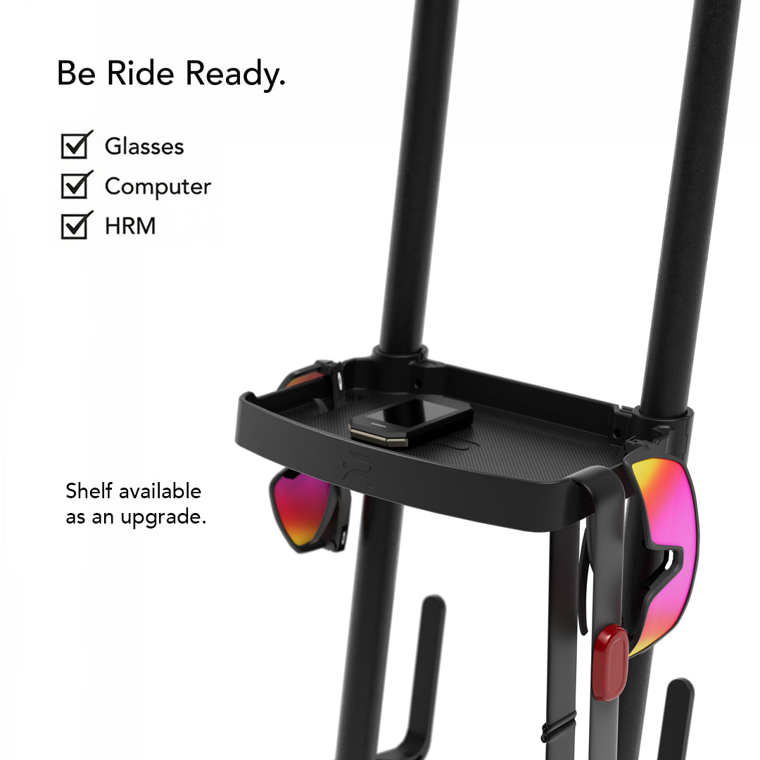 Close-up of the Ready Rack accessory shelf holding cycling glasses and a bike computer, with checklist overlay noting it stores glasses, computer, and HRM under the headline "Be Ride Ready."