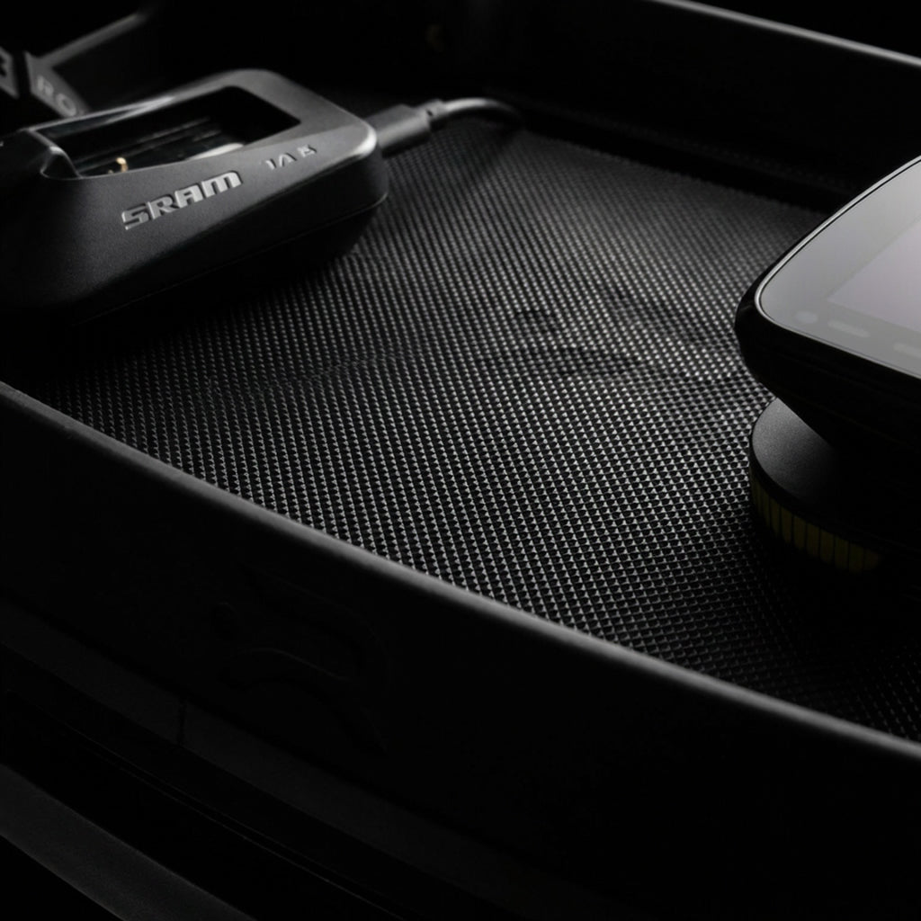 Close-up detail shot of the Ready Rack's textured non-slip shelf surface with a SRAM component and a smartphone resting on it.