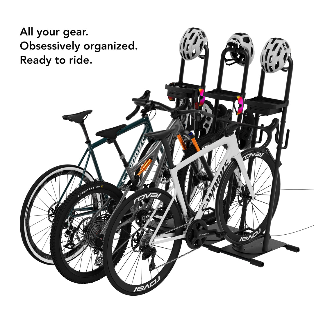 Three bikes (mountain, gravel, and road) each stored on their own linked Ready Rack units with helmets mounted on top, with overlay text: "All your gear. Obsessively organized. Ready to ride."
